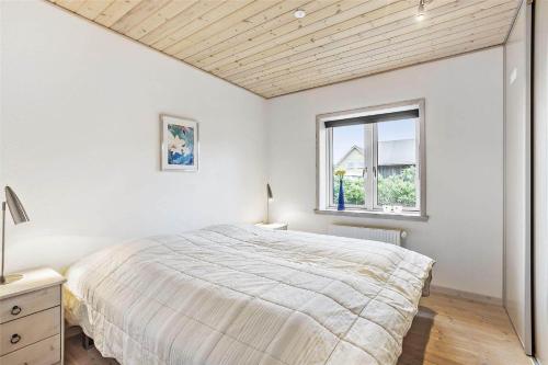 a white bedroom with a large bed and a window at 138-Ringkobing-Sondervig-Klitvej-3 in Søndervig