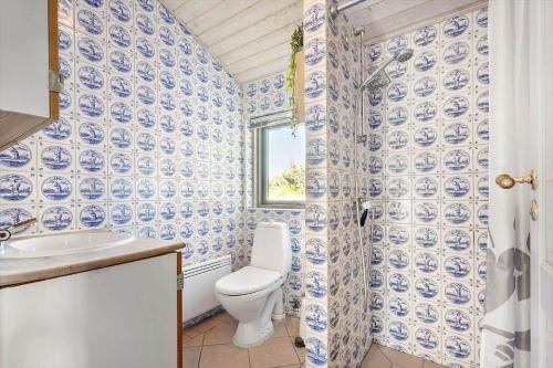 a blue and white bathroom with a toilet and a window at 2202-Ringkobing-Lyngvejen-73 in Klegod