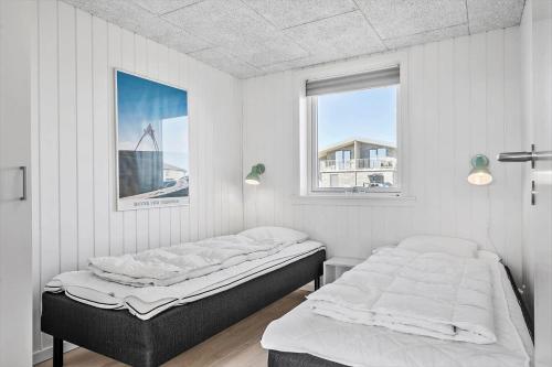 two beds in a white room with two windows at 1194-Ringkobing-Havstien-203 in Søndervig