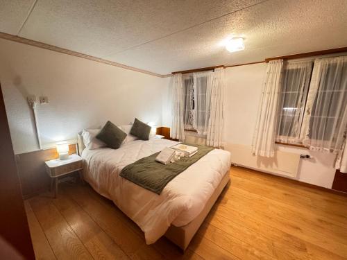 a bedroom with a large bed with a nightstand and two windows at HausHarder Rooms in Gommiswald