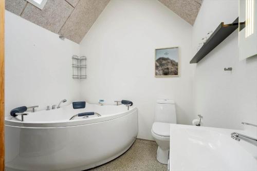 a white bathroom with a tub and a toilet at 1196-Ringkobing-Sivsangervej-24 in Nørby