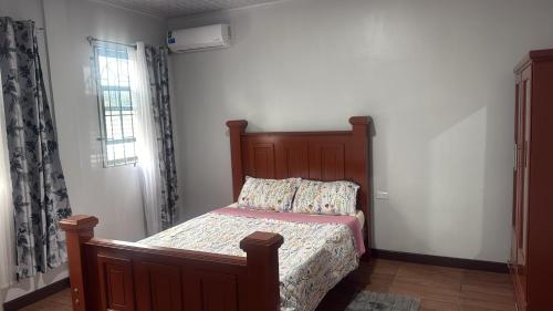 a bedroom with a bed with a wooden headboard at Peaceful Paraiso in New Amsterdam