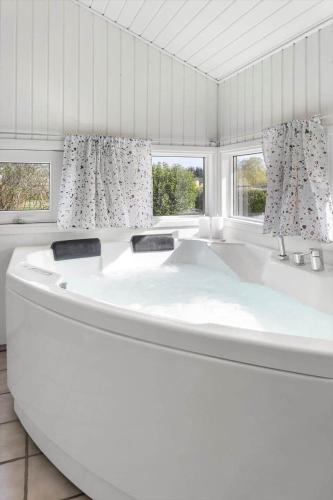 a large white tub in a room with two windows at FY386-Hesselager-Stentoften-22 in Hesselager