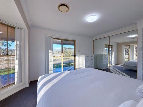 a white bedroom with a large bed and large windows at Marrangaroo Meadows in Marrangaroo