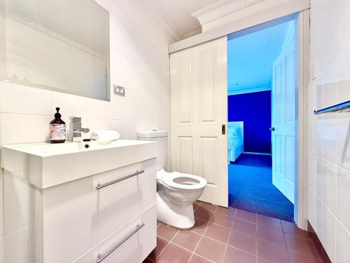 a white bathroom with a toilet and a sink at Marrangaroo Meadows in Marrangaroo