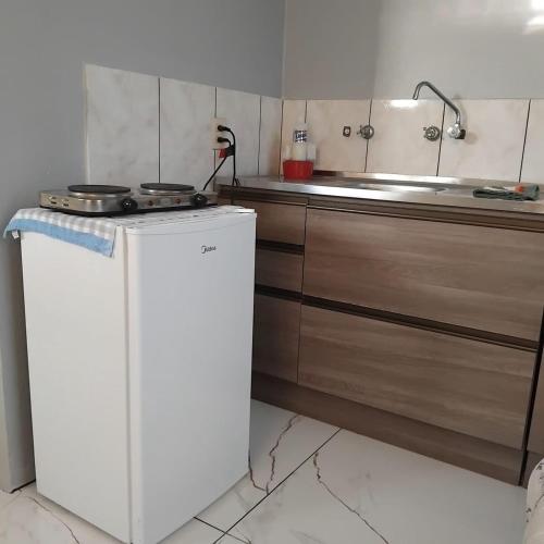 a kitchen with a stove and a white refrigerator at Small and cozy in Ijuí