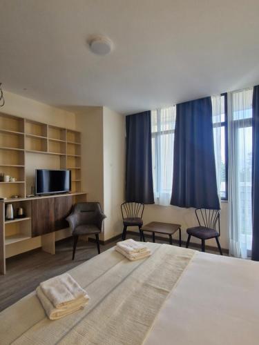 a bedroom with a bed and chairs and a television at Nike aghmashenebeli str 158 in Kobuleti