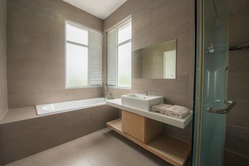 a bathroom with a sink and a tub and a mirror at New Shamrock Beach Villas Seaview in Batu Ferringhi
