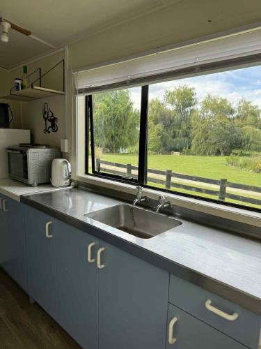 a kitchen with a sink and a large window at Lime Ridge Farm Cottage in Fairlie