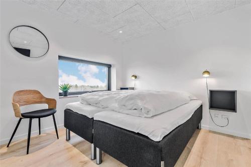 a bedroom with a bed and a chair and a television at 8912-Allingabro-Fyrrevej-6 in Allingåbro