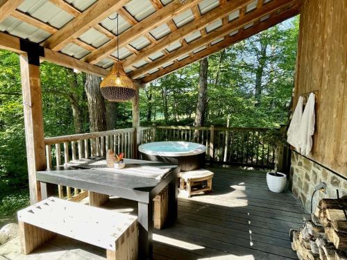 a wooden deck with a picnic table and a bench at Le 14 Chalets Howard - Spa-Shower-Hammock-Bromont in Bromont