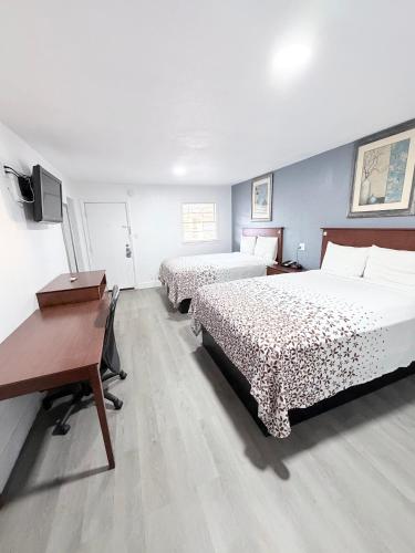 a bedroom with two beds and a desk and a computer at Economy Inn in Longview