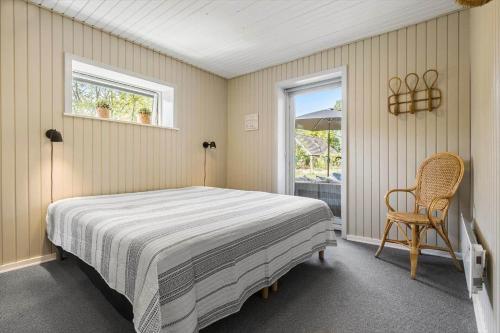 a bedroom with a bed and a chair and a window at 8915-Glesborg-Zachosvej-5 in Glesborg