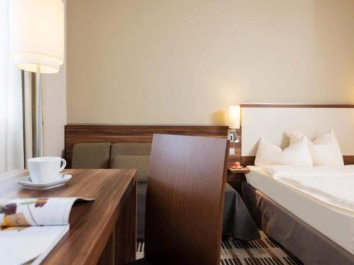 a hotel room with a bed and a desk with a cup at Sunday Saarbruecken Sued Standard Room in Saarbrücken