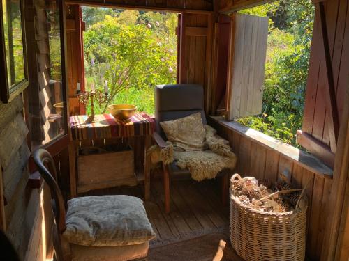 a porch of a cabin with a chair and a window at Riverside Cabin in Akaroa in Akaroa
