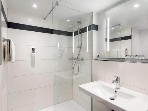 a white bathroom with a shower and a sink at Sunday Hotel Bielefeld Standard King Room in Bielefeld