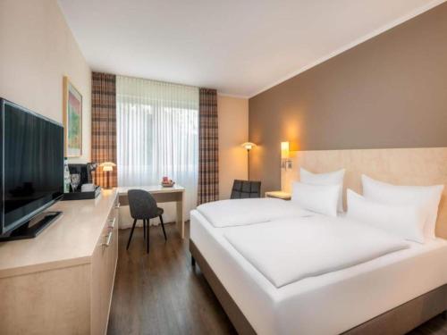 a hotel room with a large white bed and a desk at Sunday Hotel Bielefeld Standard King Room in Bielefeld