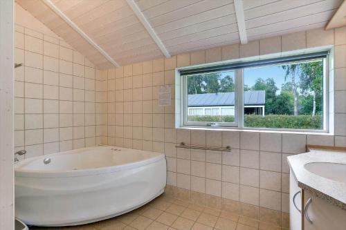 a white tub in a tiled bathroom with a window at 8519-Grenaa-Nobilisvej-13 in Grenå