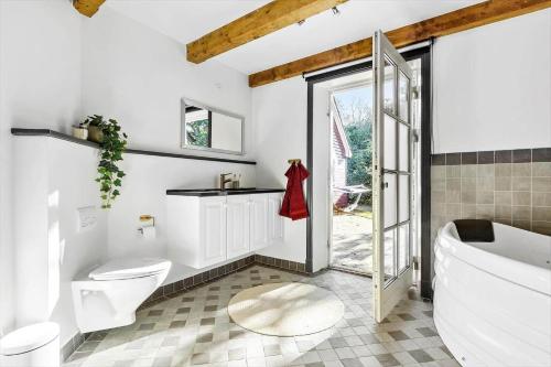 a bathroom with a tub and a toilet and a sink at 8514-Grenaa-Sortebaervej-16 in Grenå