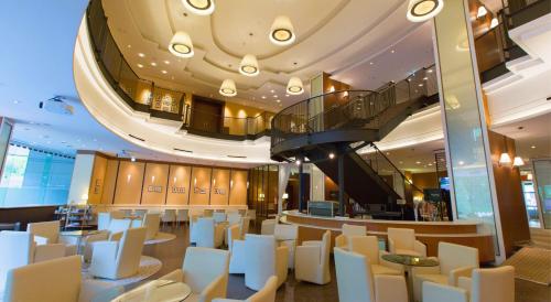 a restaurant with white chairs and a spiral staircase at Premier Hotel Nakajima Park Sapporo in Sapporo
