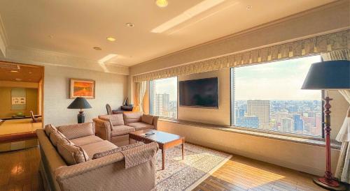 a living room with two couches and a large window at Premier Hotel Nakajima Park Sapporo in Sapporo