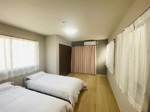 a bedroom with two beds and a window at Villa KENZO JR弁天町駅4分地下鉄駅6分 USJ 梅田 大阪城公園直通 駐車場付きモダン一軒家 in Osaka