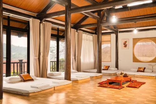 a large room with three beds and a table at Trám House in Cao Phong