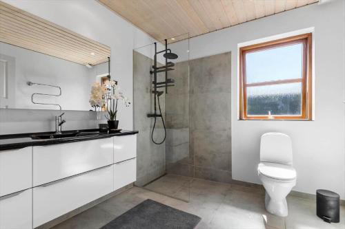 a bathroom with a toilet and a sink and a window at 8565-Grenaa-Kystvej-58 in Grenå