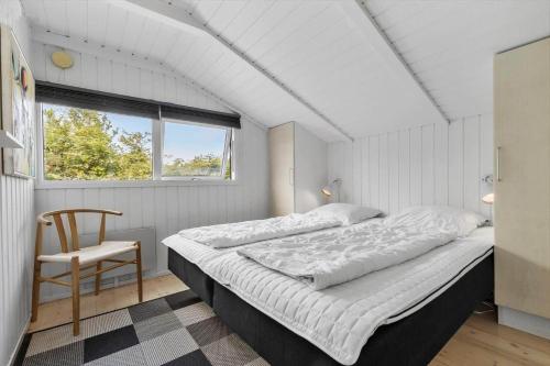 a bedroom with a large bed and a chair at 8927-Allingabro-Nordvangsvej-27 in Allingåbro