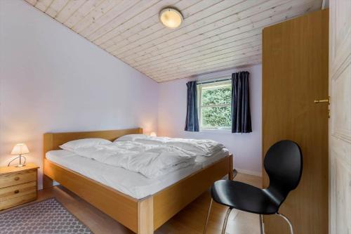 a bedroom with a bed and a black chair at 8960-Orsted-Ternevej-15 in Ørsted
