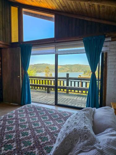 a bedroom with a large window with a view of the water at Casa Amanecer Vichuquén in Vichuquén Lake
