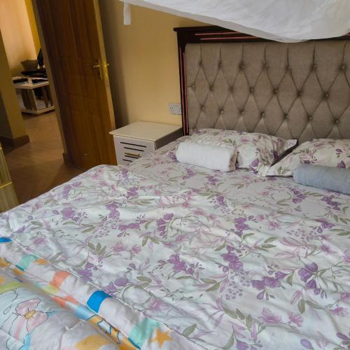a bedroom with a bed with a floral bedspread at Snug Spot BnB-Mwea in Thiba