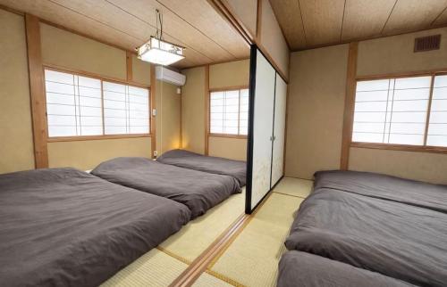 three beds in a room with three windows at Guesthouse すえ in Mashizume
