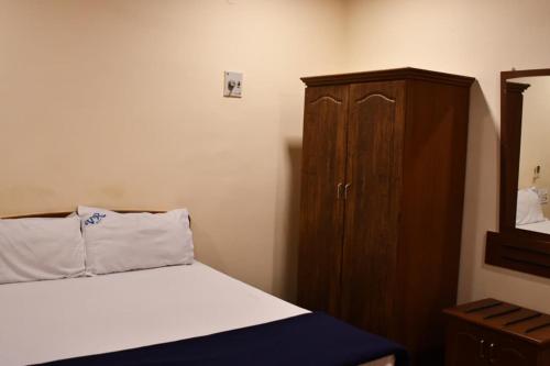 a bedroom with a bed and a wooden cabinet at Vybhav Residency AC in Anantapur