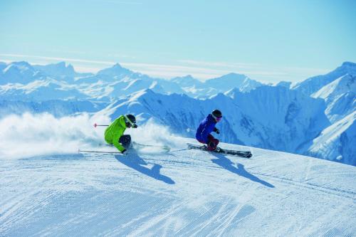 two people are skiing down a snow covered mountain at Hotel Laaxerhof in Laax