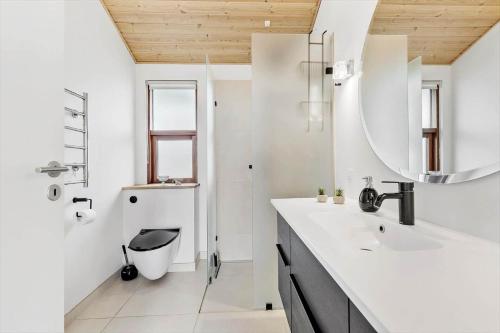 a white bathroom with a sink and a mirror at 84164-Ronde-Stenhojvej-17 in Rønde