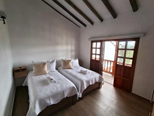 a bedroom with two beds with white sheets and a window at Hotel Boutique Villa Amonita in Villa de Leyva