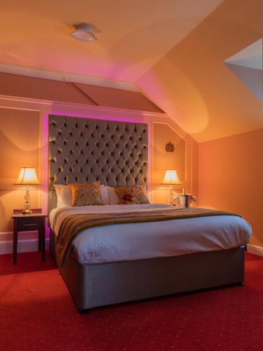 a bedroom with a large bed with purple lighting at Rogerthorpe Manor Hotel in Pontefract