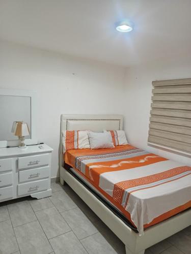 a white bedroom with a bed and a nightstand at Vista Colonial, en el Residencial Riviera Colonial in Calero