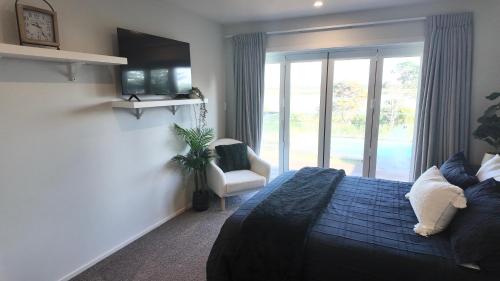 a bedroom with a bed and a chair and a window at Riverside Retreat with River views in Auckland