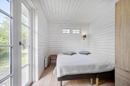 a bedroom with a bed in a white room with windows at 8242-Knebel-Uraniavej-5 in Knebel