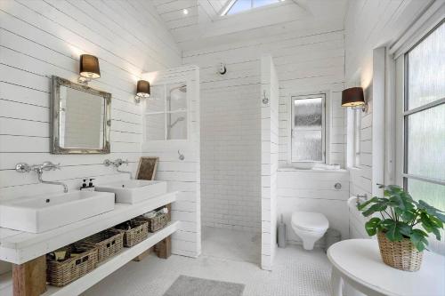 a white bathroom with two sinks and a toilet at 8242-Knebel-Uraniavej-5 in Knebel