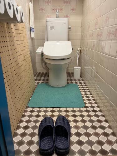 a bathroom with a toilet and a pair of shoes at Peace House Isonoura in Wakayama