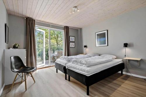 a bedroom with a bed and a chair and a window at 84264-Ronde-Enebaervej-4 in Rønde