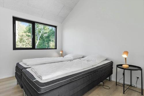a bedroom with a bed with white sheets and a window at 8243-Knebel-Metholmvej-18 in Knebel