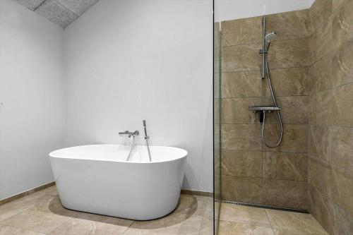 a bathroom with a white tub and a shower at 8243-Knebel-Metholmvej-18 in Knebel