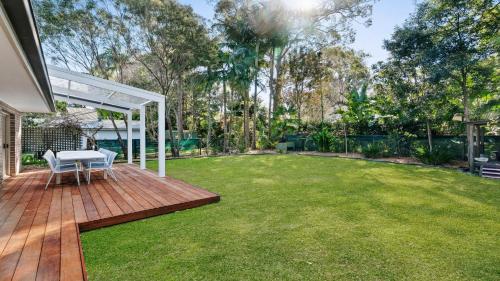 a backyard with a lawn and a white pergola at Gemburra By Holidayco in Pearl Beach
