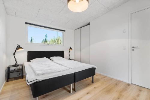 a white bedroom with a bed and a window at 8244-Knebel-Metholmvej-20 in Knebel