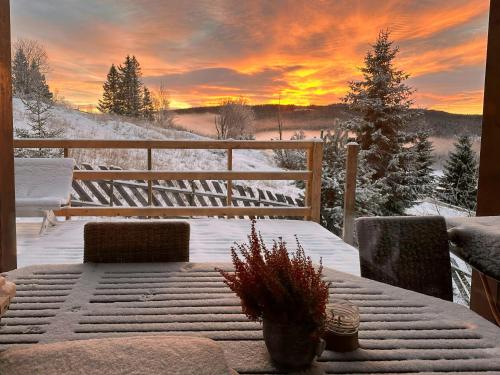 a patio with a table in the snow with a sunset at Architect-Designed Log Cabin By Myllavannet in Lunner