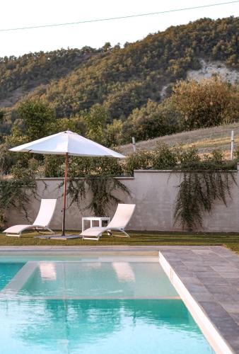 two chairs and an umbrella next to a swimming pool at Mountain Farmhouse Between Parma And Cinque Terre in Solignano